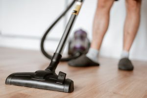 man cleaning floor with vacuum cleaner