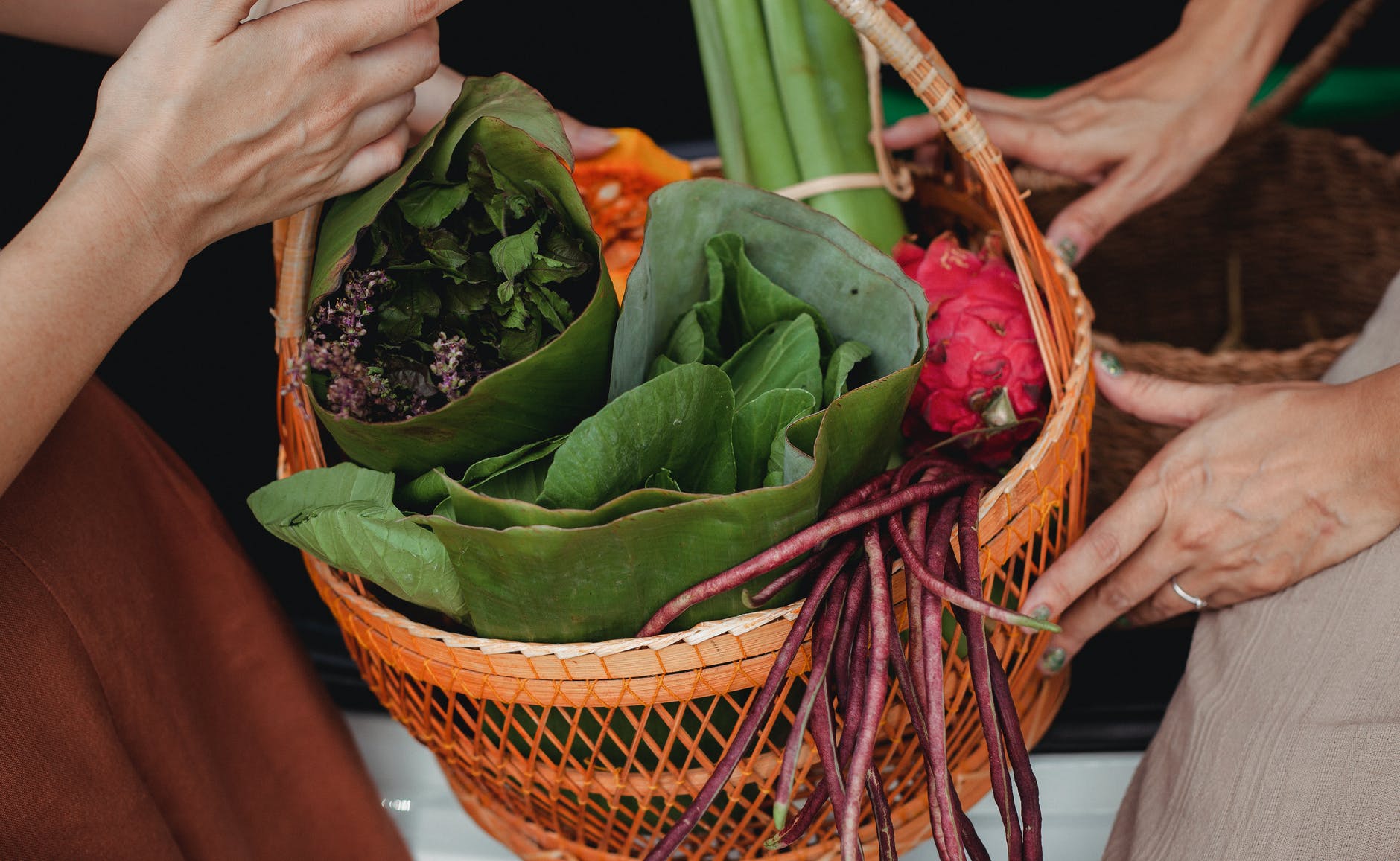 crop women showing basket with green vegetables and herbs