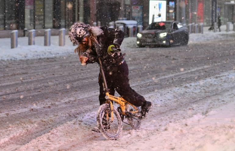 a cyclist struggles through snow in new york