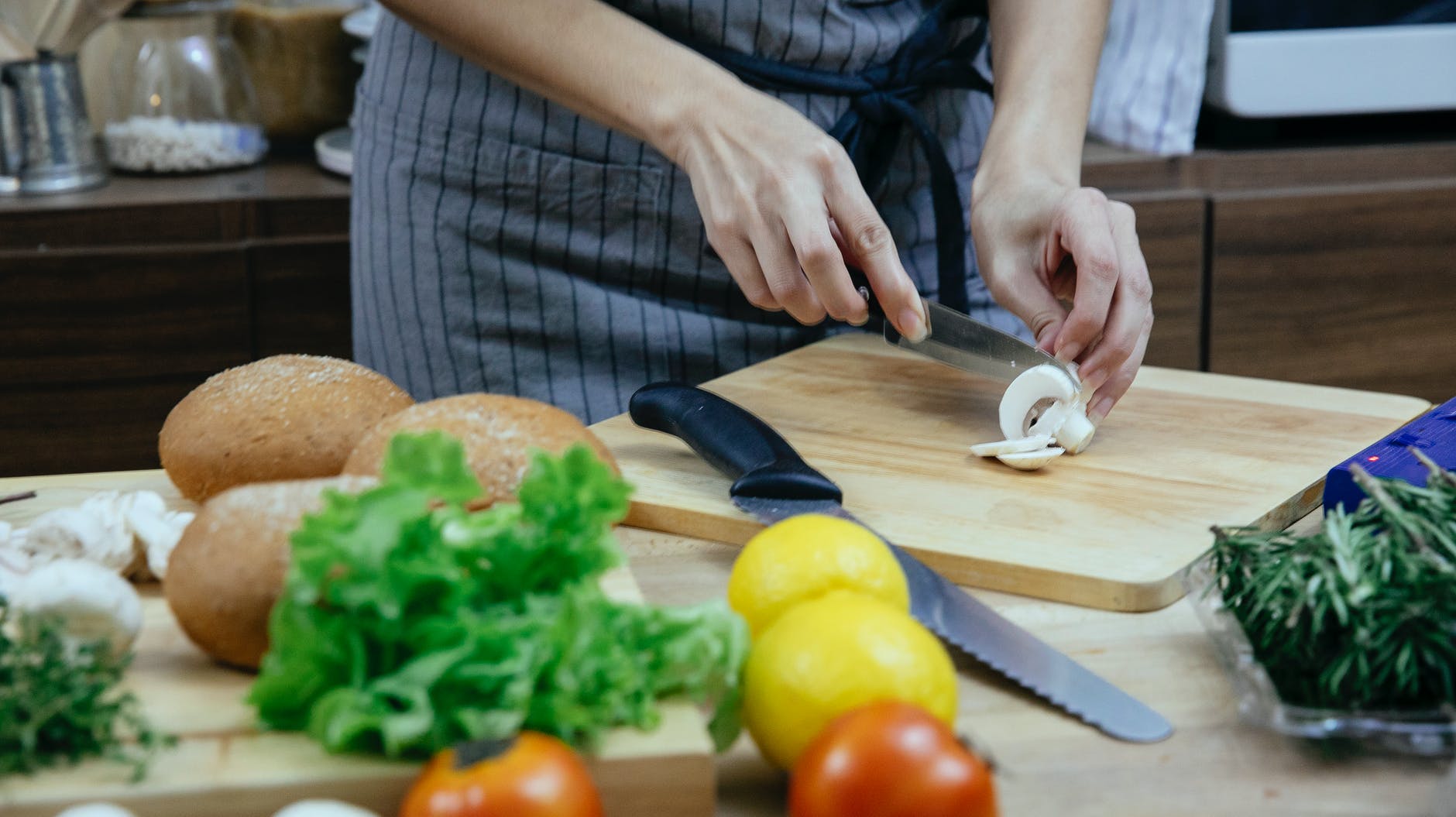 unrecognizable woman chopping champignons on cutting board while preparing healthy dish