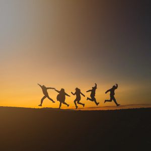 unrecognizable happy people jumping in sunset