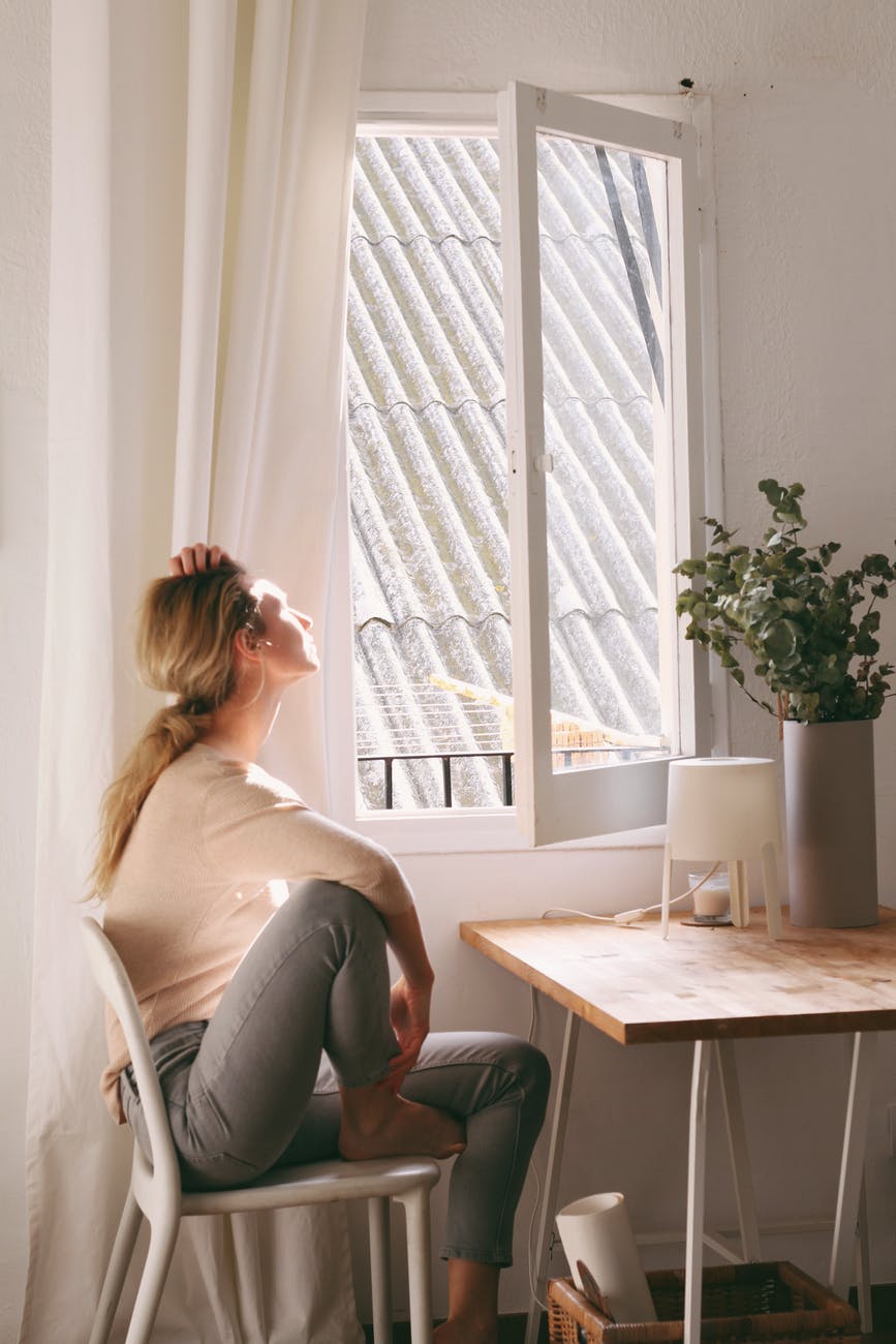 woman sitting on a chair next to a window | Curb Your Procrastination With These Tips