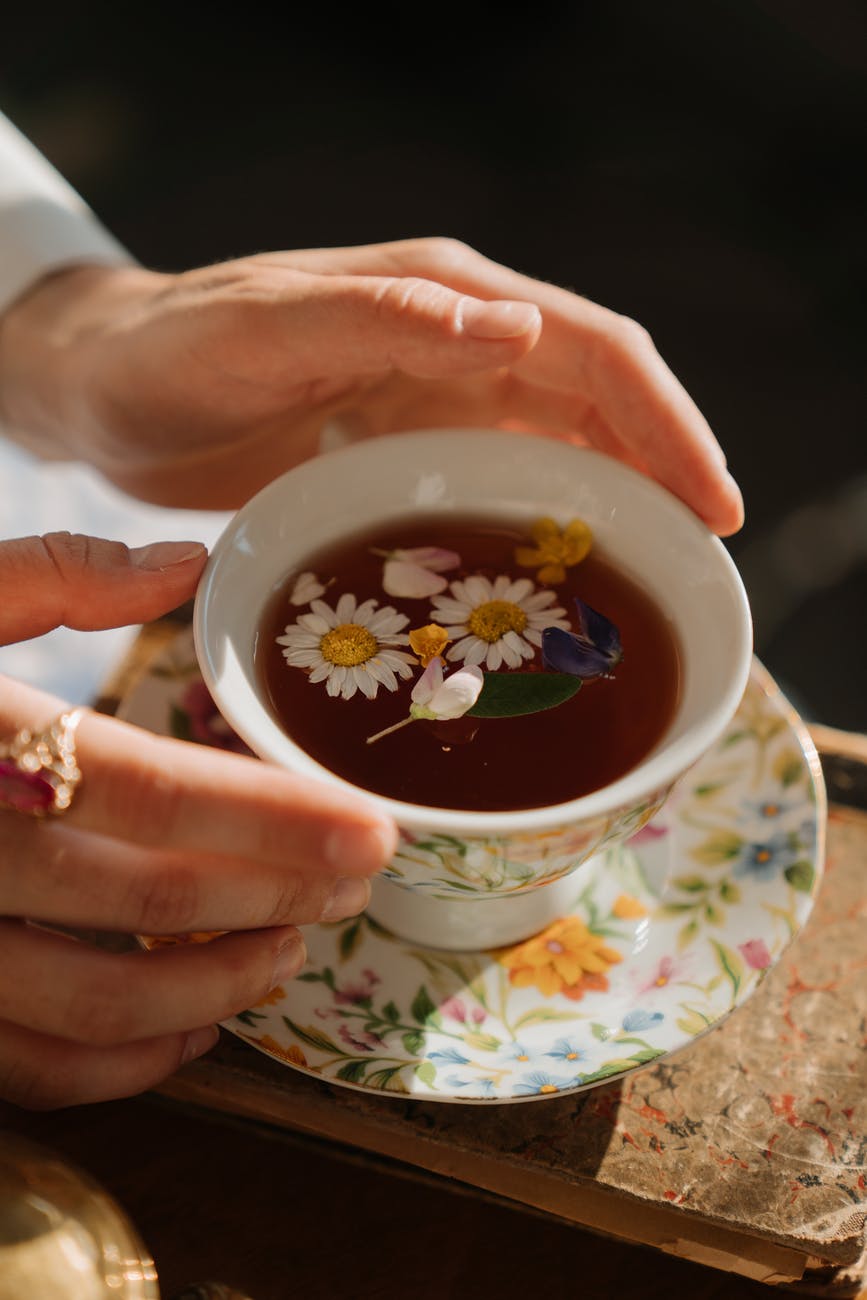 person holding white ceramic teacup with tea