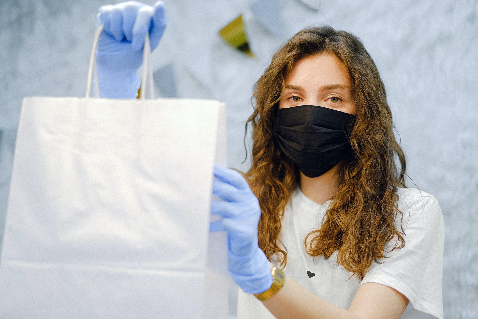 woman with face mask and latex gloves holding a shopping bag