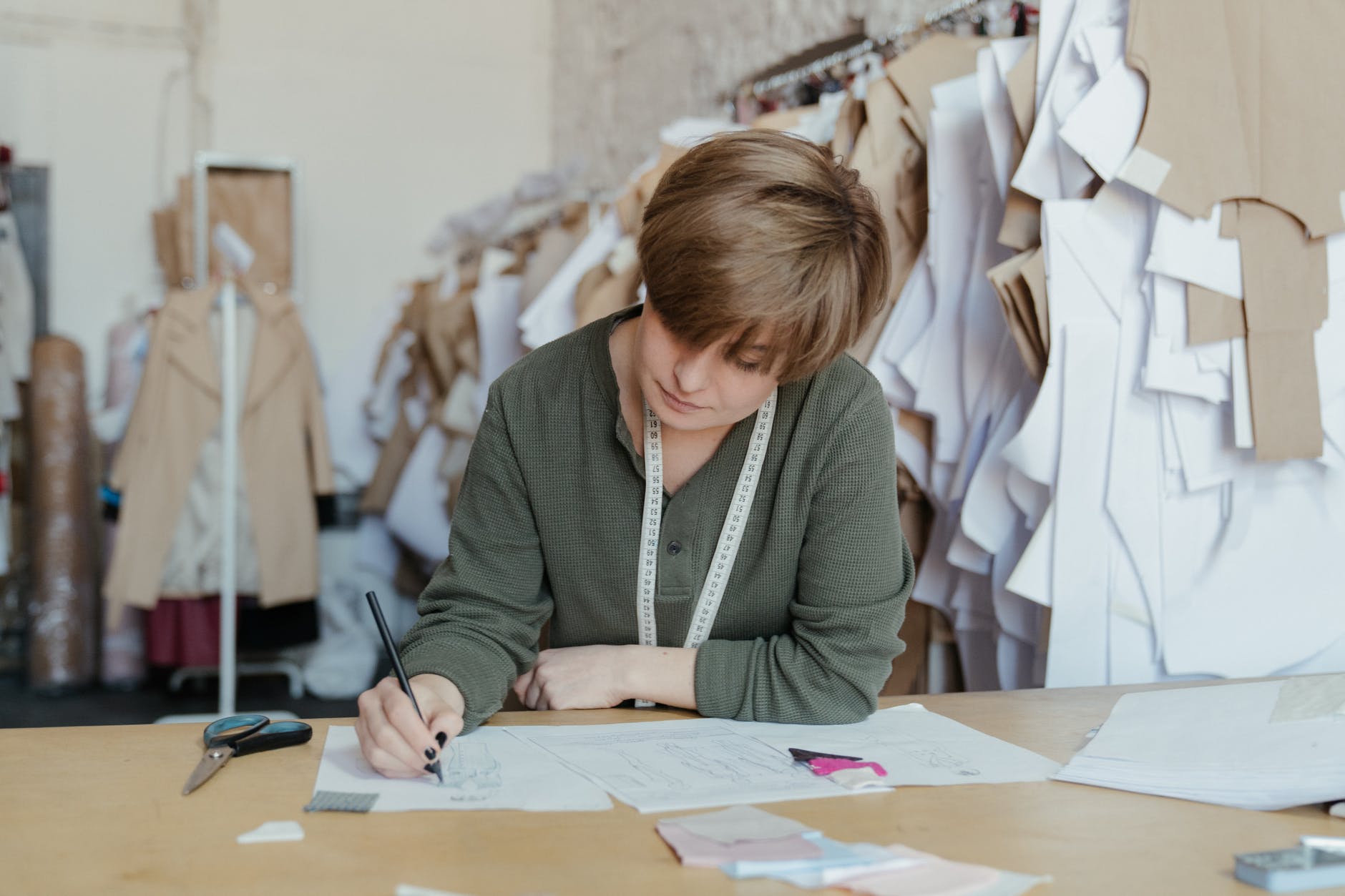 woman in gray cardigan writing on white paper