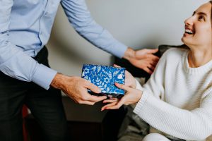 photo of person handing gift to woman